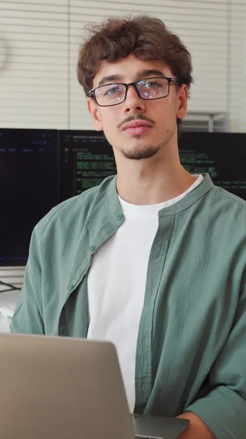 Smiling Young Software Developer Working on Laptop in Bright Modern Office 動画素材 345880417