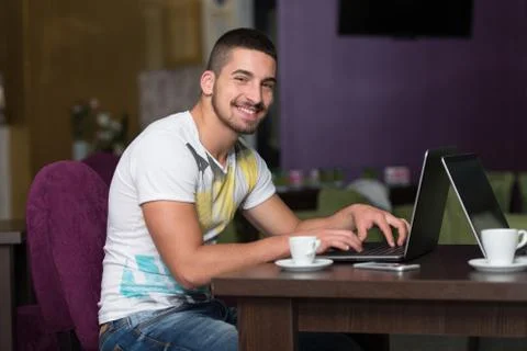 Smiling young student in cafe using laptop Stock Photos