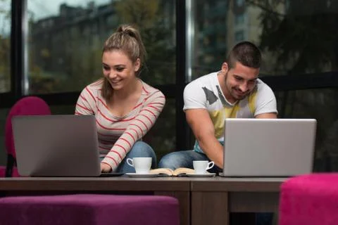 Smiling young students in cafe using laptop Stock Photos