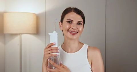 Smiling young woman with braces using dental irrigator Stock Footage 306979987