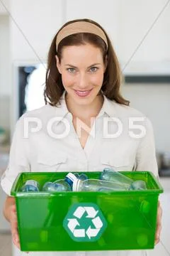 Smiling young woman carrying box with recycling symbol Stock Photos