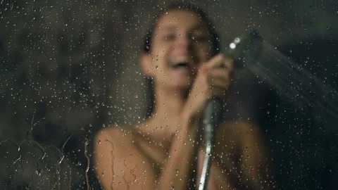 Smiling young woman having fun and pouring water at the bathromm glass. Stock-Footage 113682212