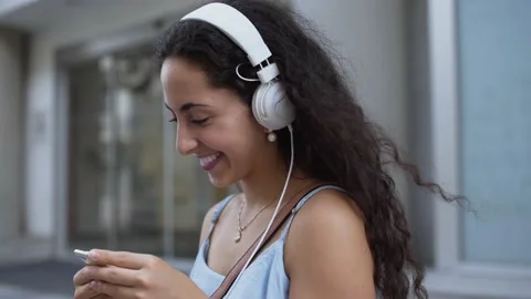 Smiling young woman with headphones having fun listening to podcast Stock Footage