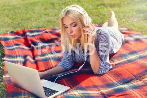 Smiling Young Woman With Laptop Computer And Headphones Outdoors