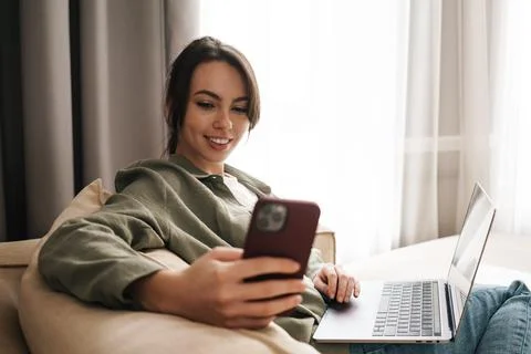 Smiling young woman with laptop computer at home Stock Photos