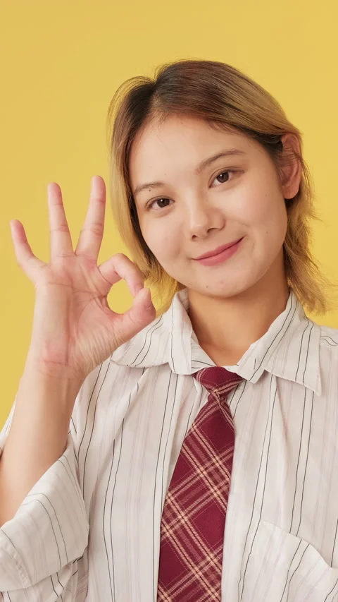 Smiling young woman looking at camera showing ok gesture isolated on yellow Stock Footage 254915431