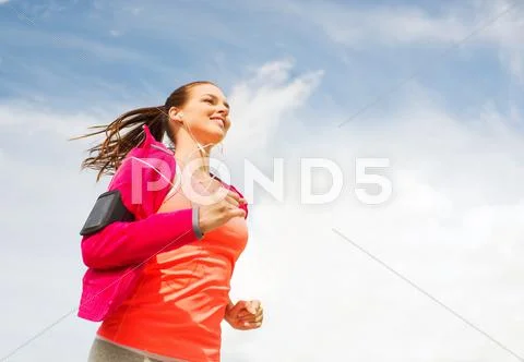 Smiling young woman running outdoors Stock Photos