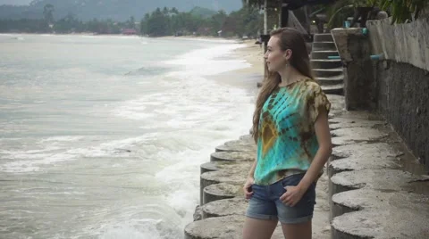 Smiling Young Woman Standing on the Coast on the Background of Crashing Waves Stock Footage 59794204