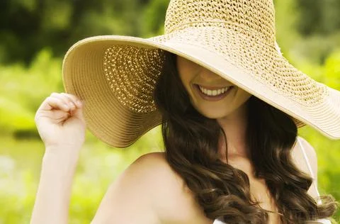 Smiling young woman in sun hat covering her eyes. Stock Photos