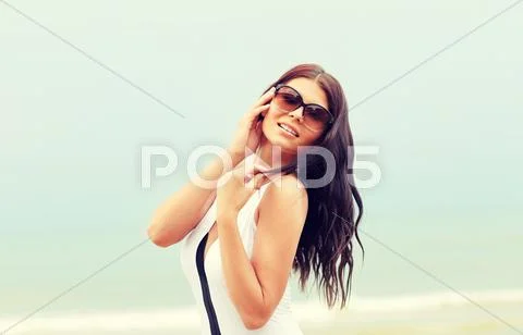 Smiling young woman with sunglasses on beach Stock Photos