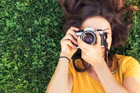 Smiling young woman using a camera to take photo. Stock Photos