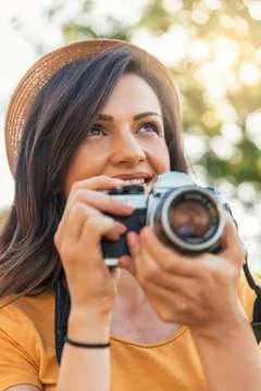 Smiling young woman using a camera to take photo. Stock Photos