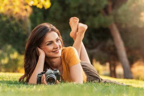 Smiling young woman using a camera to take photo. Stock Photos