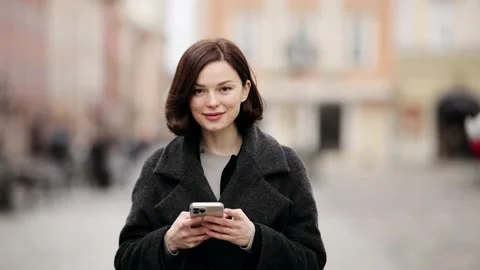 Smiling young woman with using smart phone while walking down the street Stock Footage 151858404