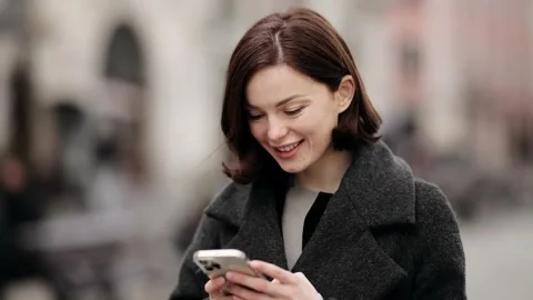Smiling young woman using smart phone on street. Attractive young blonde Woman Stock Footage 152477833
