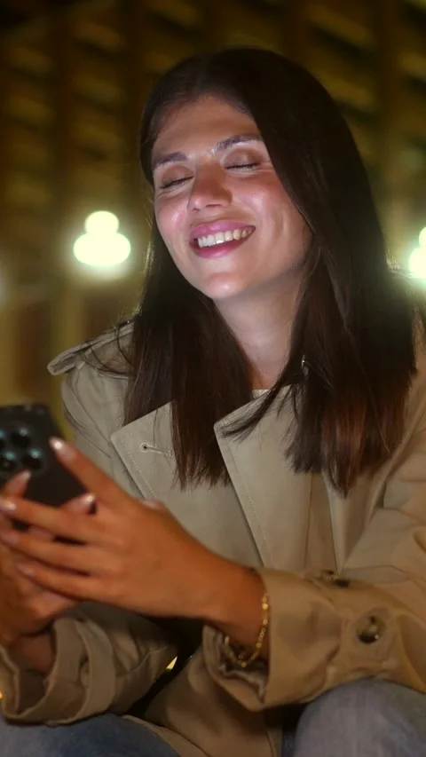 Smiling young woman using smartphone at night in the city Stock Footage 317376689