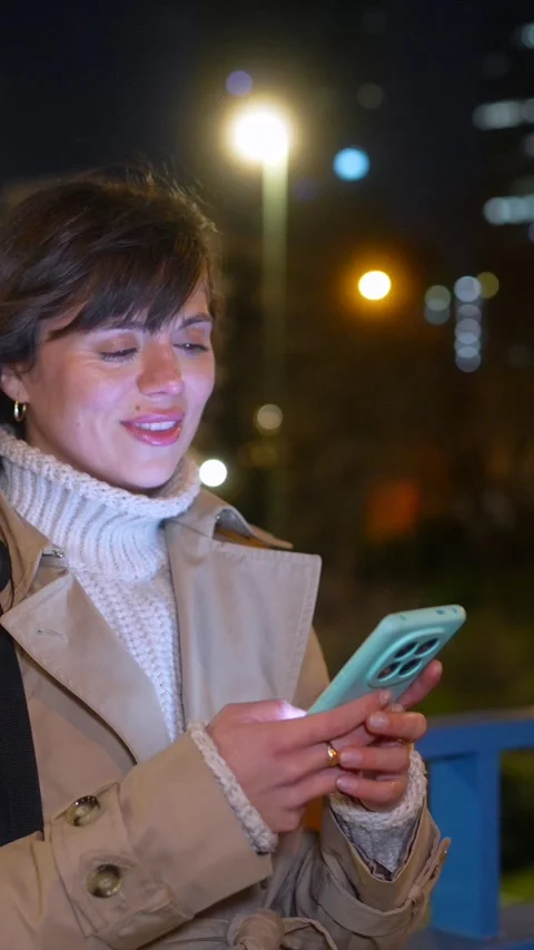 Smiling young woman using smartphone at night in city Stock Footage 328911589
