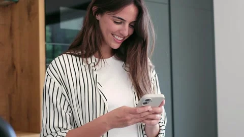 Smiling young woman using smartphone at home Stock Footage 335588397