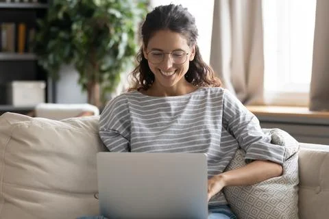 Smiling young woman work online on laptop at home Stock Photos