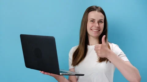 Smiling young woman working on laptop typing showing thumb up like gesture Stock Footage 153089853