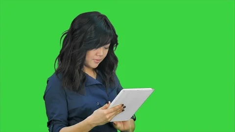 Smiling young woman working on tablet computer on a Green Screen, Chroma Key Stock Footage