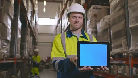 Smiling young worker holding his digital tablet in a large warehouse Stock Footage 123280610