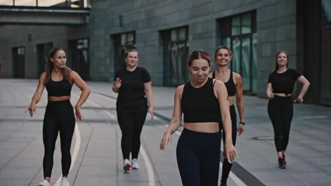 Smiling zumba class dancing in the city at night time. People in black Stock Footage 158922832