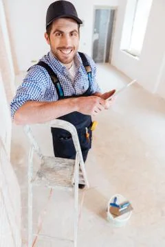 Smilling handyman using pc tablet computer while working 스톡 사진