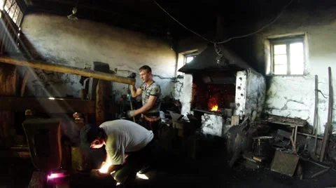 A Smith and His Apprentice Workpiece Using a Ancient Water-Powered Smithy in Video stock 59761950