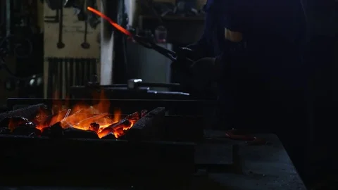 The smith takes a red-hot iron hook from the fire and treats it with a hammer Stock Footage 79148964