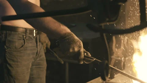 The smith warms the metal in open fire, side view Stock Footage 109604594