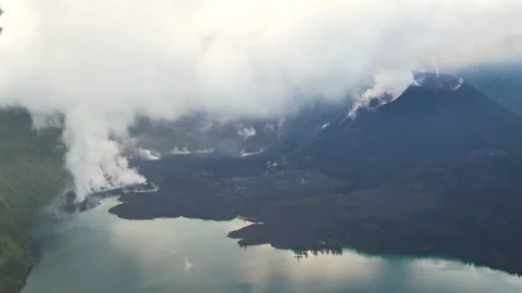 Smoke from the active volcano Rinjani surrounded by water, in Indonesia Stock Footage 221873114