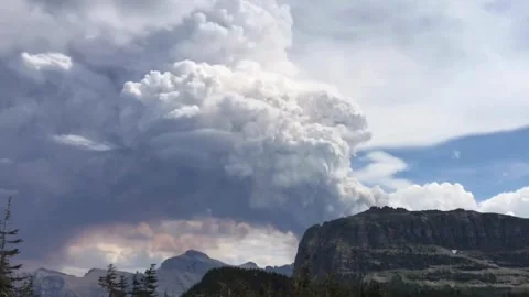 Smoke and clouds together over a forest mountain range Stock-Footage 336474075
