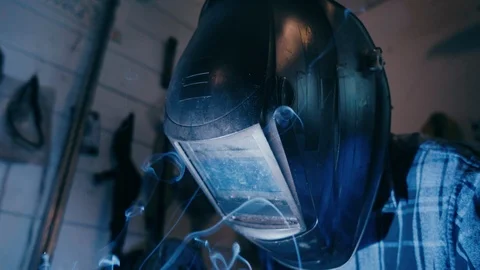 Smoke and sparks explode below man in welding mask Видео 104078195
