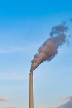 Smoke belching out of a chimney stack at a power station Stock Photos