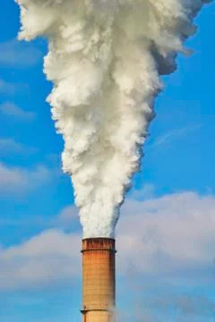 Smoke bellowing from the smoke stack of a electic power plant Stock Photos