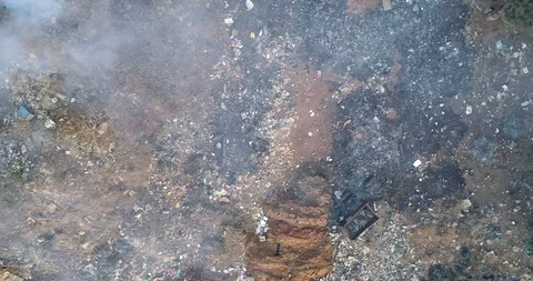 Smoke blowing over trash creating an environmental hazard drone shot Video stock 95138272
