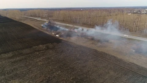 Smoke from Burning Grass on the Side of the Road Creeps along the Road and the F Stock Footage 127855636