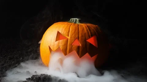 Smoke coiled from the face of a Halloween Pumpkin with different colored ligh Stock Footage 214801246