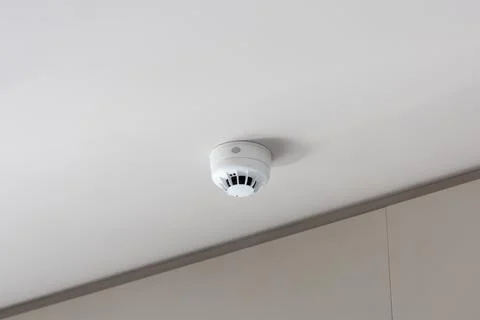 Smoke detector mounted on plain ceiling, fire alarm system Stock Photos