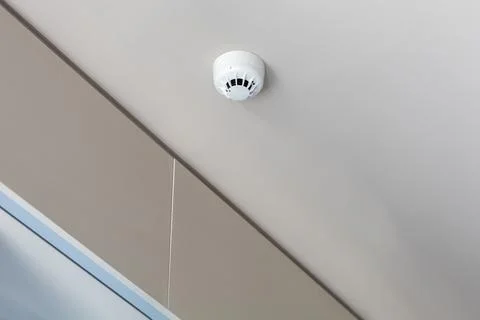 Smoke detector mounted on plain ceiling, fire alarm system Stock Photos