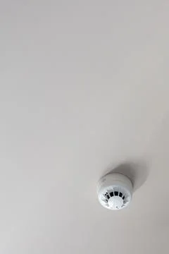 Smoke detector mounted on plain ceiling, fire alarm system, copy space Stock Photos