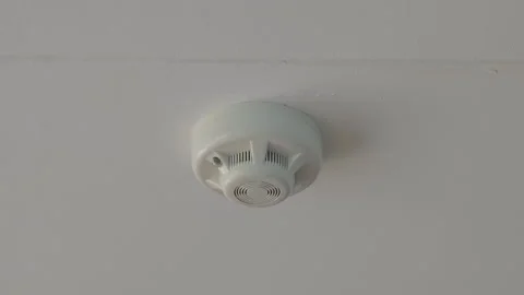 Smoke detector mounted on a white ceiling with a red led light blinking Stock Footage 345600885