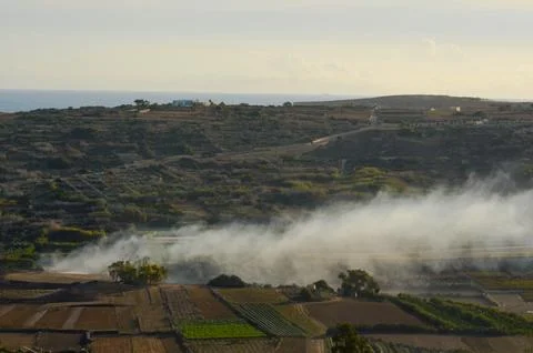 Smoke Drift Over Countryside Fields and Hills Stock Photos