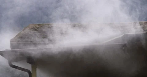 Smoke escaping from around gutter on the eaves of a burning house Stock Footage 59222429