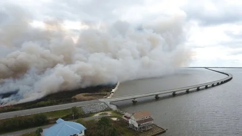 Smoke from a grassland fire fills the air reducing visibility near a bridge Stock Footage