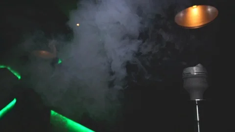 Smoke from the hookah dissolves in the air of bar room or night club. Slow Video stock 129358570
