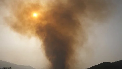 Smoke from a large fire billows into the sky as the sun sets, beach Stock Footage 111894259