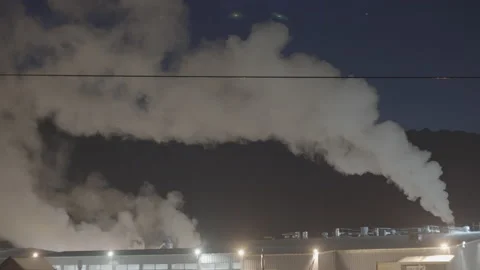 Smoke pollution rising into the night sky in front of mountain Stock Footage 225408873
