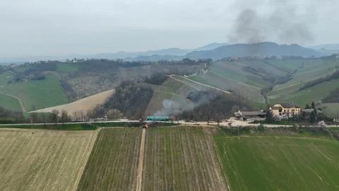 Smoke rises from burning grape branches across the rolling Piacenza hills a Foto stock